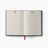 Open black journal with lined cream pages and red peppermint decorations, red ribbon bookmark