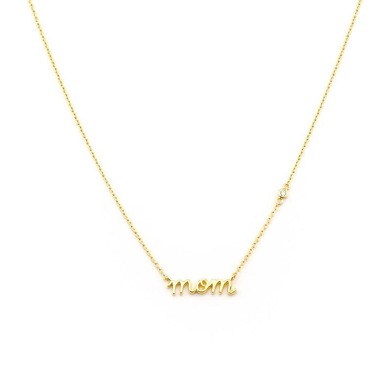 Gold cursive mom necklace with delicate chain and diamond accent on white background