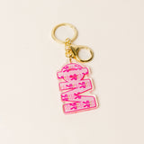 Pink sorority letter acrylic keychain with gold hardware on neutral background