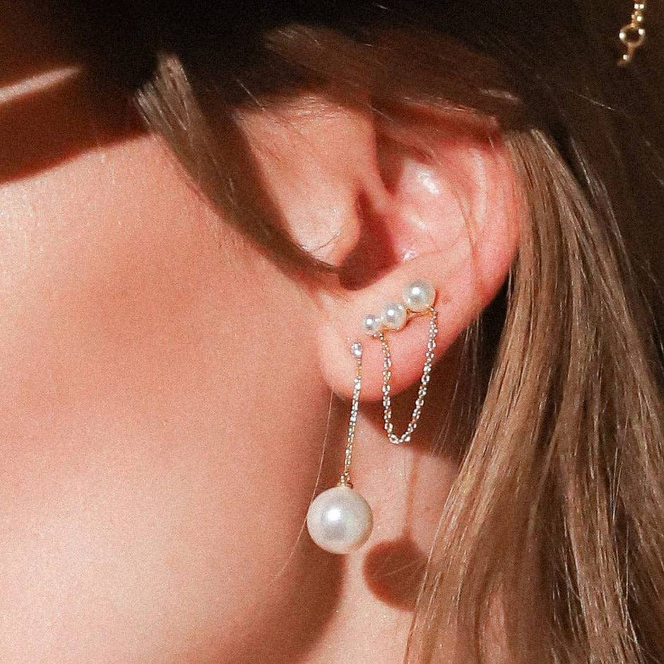 Pearl and chain stud earrings worn on model, featuring pearl studs with delicate chain drops