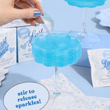 Cotton candy glitter bombs in blue cocktail glass with product packaging and instruction card displayed