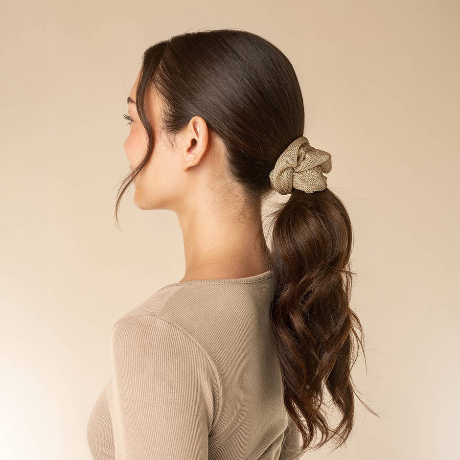 Woman wearing cream and gold satin scrunchies in ponytail hairstyle