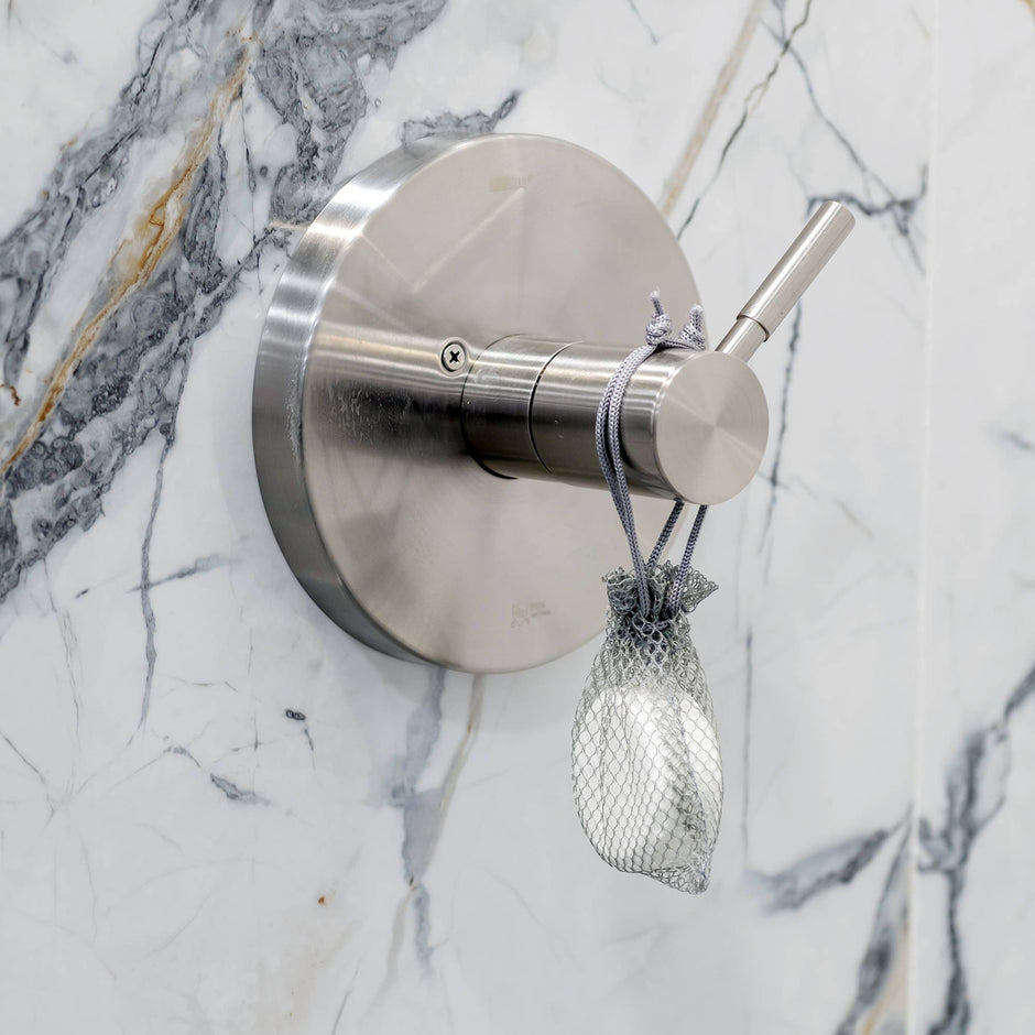 Luxe Lavender + Oat Shower Steamer Fizzy Bomb hanging from stainless steel bathroom fixture