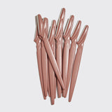 Set of rose gold eyebrow razors on a light gray background