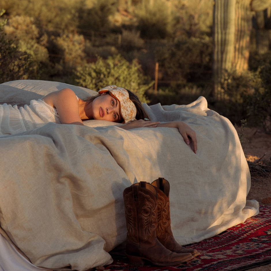 Woman wearing NODPOD Frontier weighted sleep mask while resting outdoors in desert setting