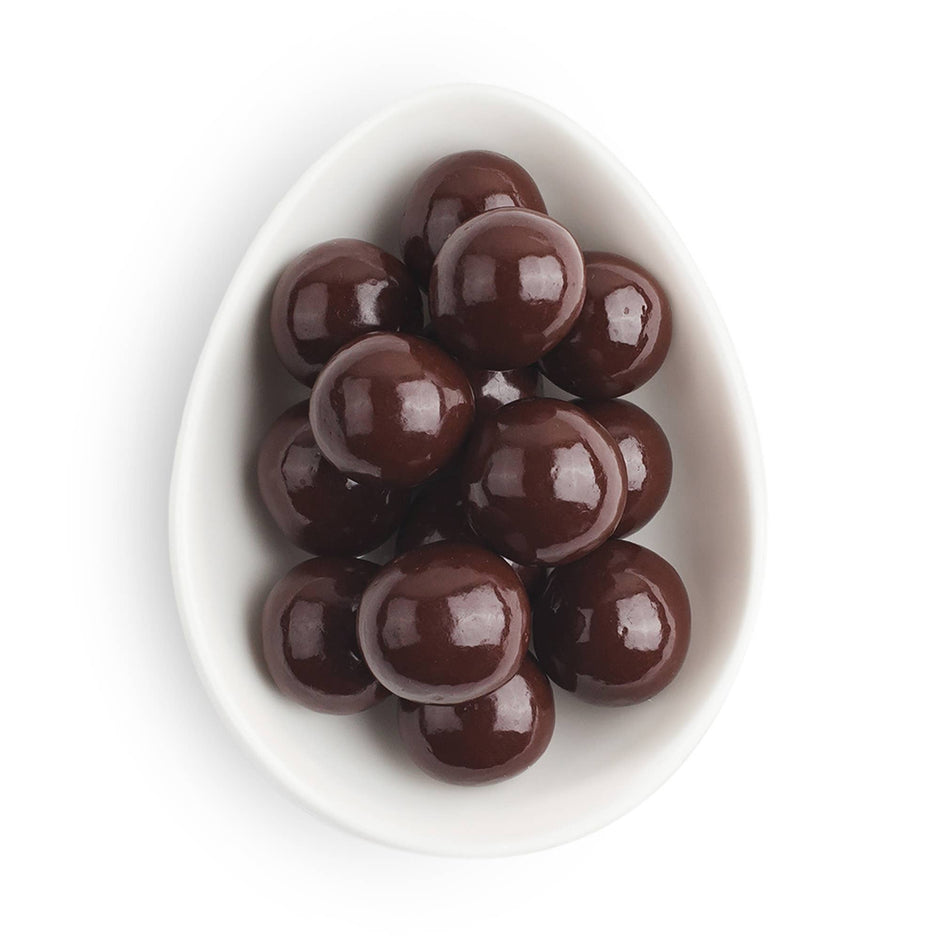 Dark chocolate sea salt caramels in white egg-shaped dish on neutral background