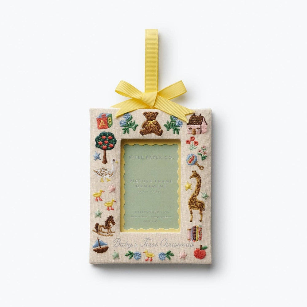 Rifle Paper Co. Baby's First Christmas picture frame ornament with embroidered toys and yellow ribbon