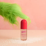 The Grinch x Kitsch hair perfume bottle with bright green fuzzy character prop against pink background