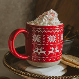 Red Fair Isle sweater stoneware mug topped with whipped cream and peppermint candy on decorative plate
