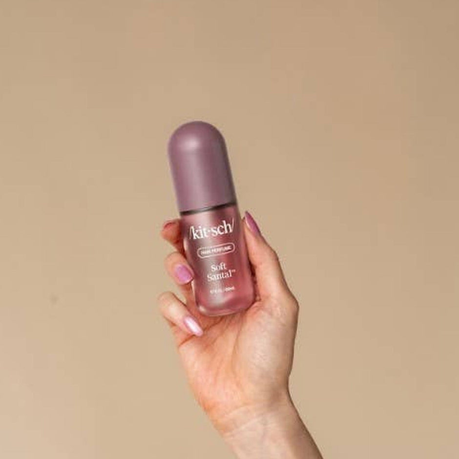 Hand holding Kitsch Soft Santal Hair & Body Perfume Mist against neutral beige background