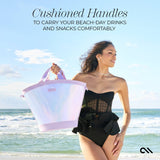 Woman holding pink cushioned cooler tote at beach with ocean waves in background