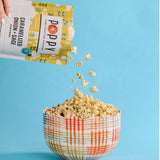 Poppy hand-crafted popcorn being poured into a checkered bowl against a blue background