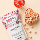 Poppy Shirley Temple popcorn in heart bowl with red beverage on neutral background