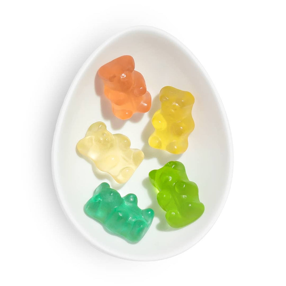 Colorful gummy bears in rainbow colors arranged in a white oval dish