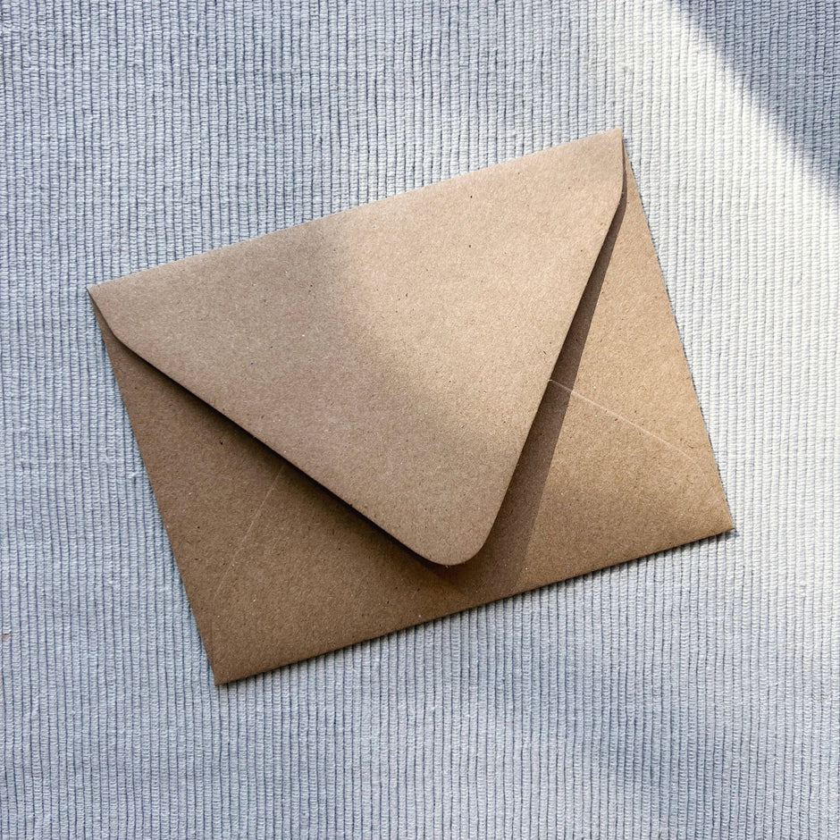 Kraft paper envelope with curved flap closure on textured white background