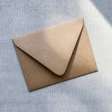 Kraft paper envelope with rounded flap closure on textured white background