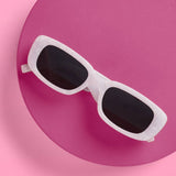 White XO FETTI Wifey sunglasses with dark lenses on pink circular background