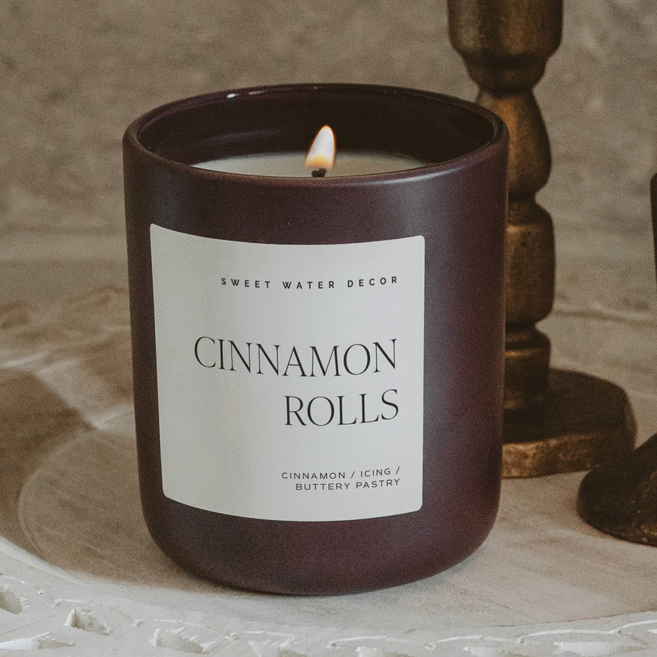 Cinnamon Rolls scented soy candle in matte jar with lit flame and bronze decor
