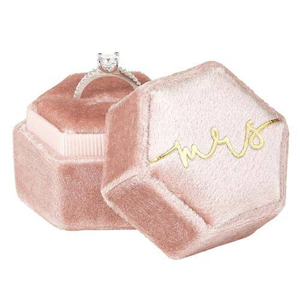 Pink velvet Mrs ring box with diamond engagement ring displayed on white background