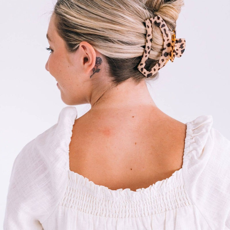 Blonde tortoise hair clip worn in updo hairstyle on model with white top