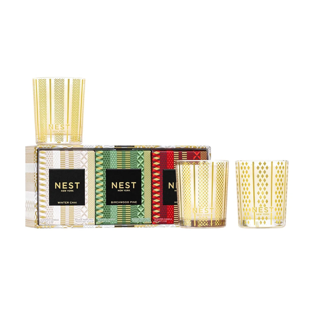 NEST New York Holiday, Birchwood Pine and Winter Chai votive candle trio, three glass votives beside their gift box on a white background