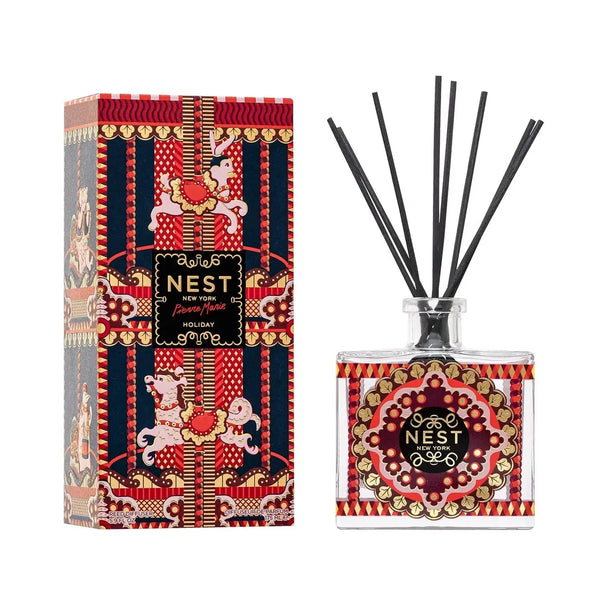 NEST New York Holiday reed diffuser with black reeds in Pierre Marie red and gold bottle beside its red gift box on a white background