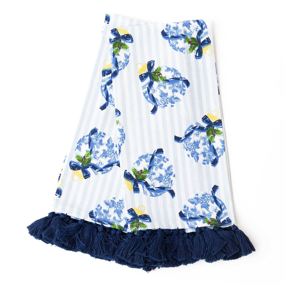 White kitchen towel with blue chinoiserie ornaments, yellow bells, green holly, and navy tassel trim