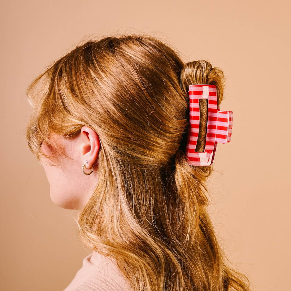Red and white striped claw clip worn in long brown hair, styled updo