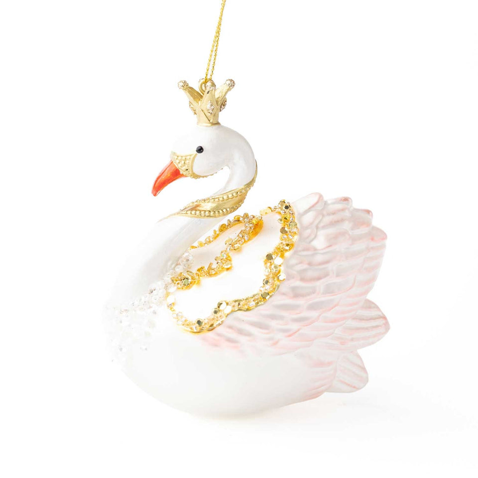 White glass swan ornament with gold crown, red beak, and pink wings against white background