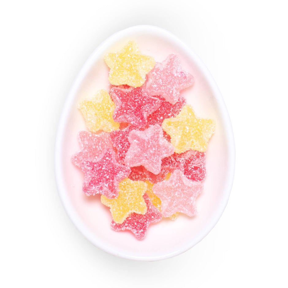 Assorted sugar-coated star-shaped gummies in pink, red, and yellow on a white oval plate.