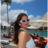 White bride sunglasses worn by woman at beach with palm trees and ocean backdrop