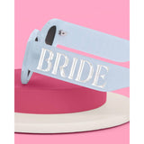 Blue bride sunglasses with 'BRIDE' text on colorful pink and cream background