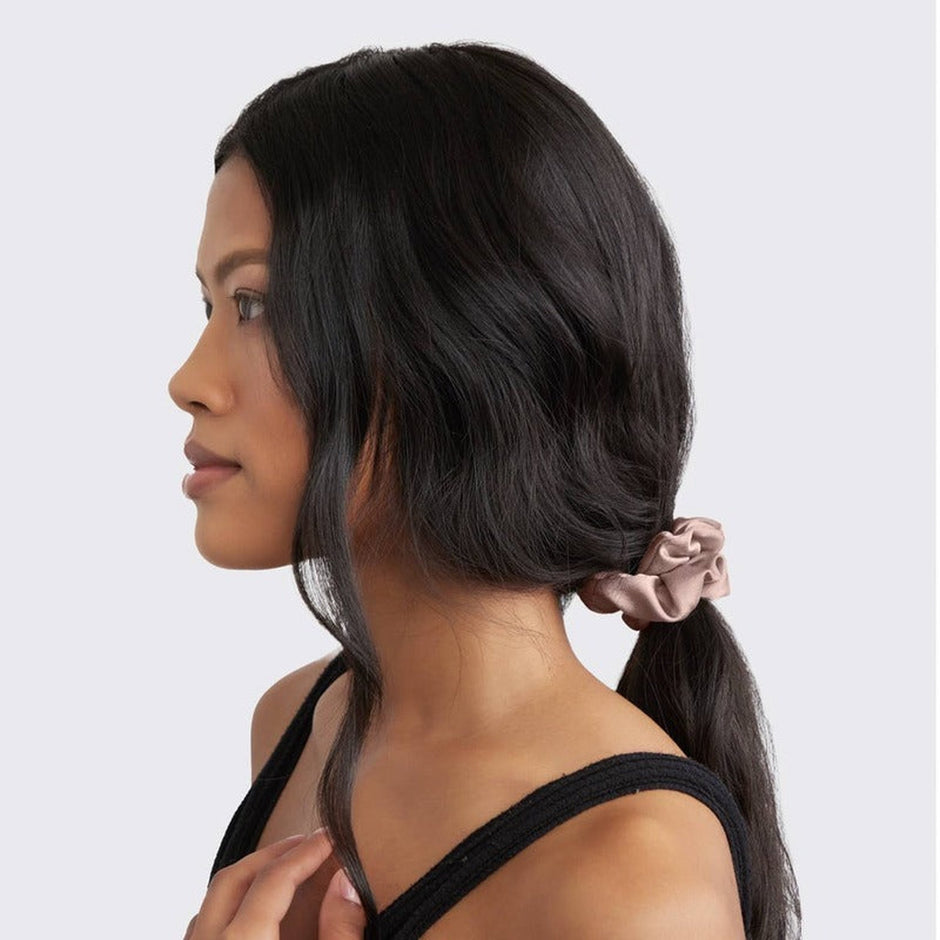 Woman wearing satin sleep scrunchie in cameo color in her long black hair