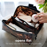 Person holding open tortoiseshell cosmetic bag filled with beauty products and brushes