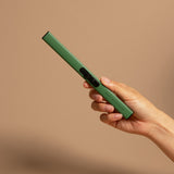 Green rechargeable electric lighter held in hand against neutral beige background