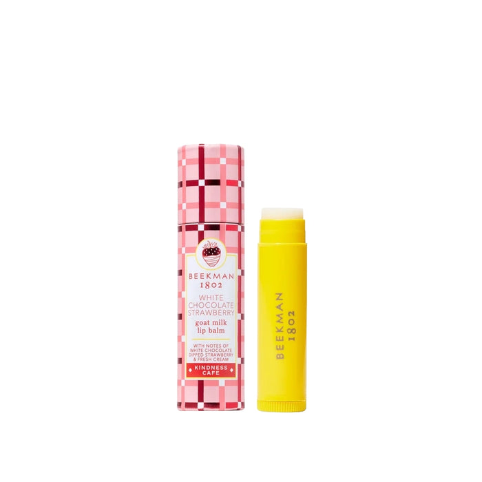 Pink plaid White Chocolate Strawberry goat milk lip balm box beside the yellow lip balm tube on a light background