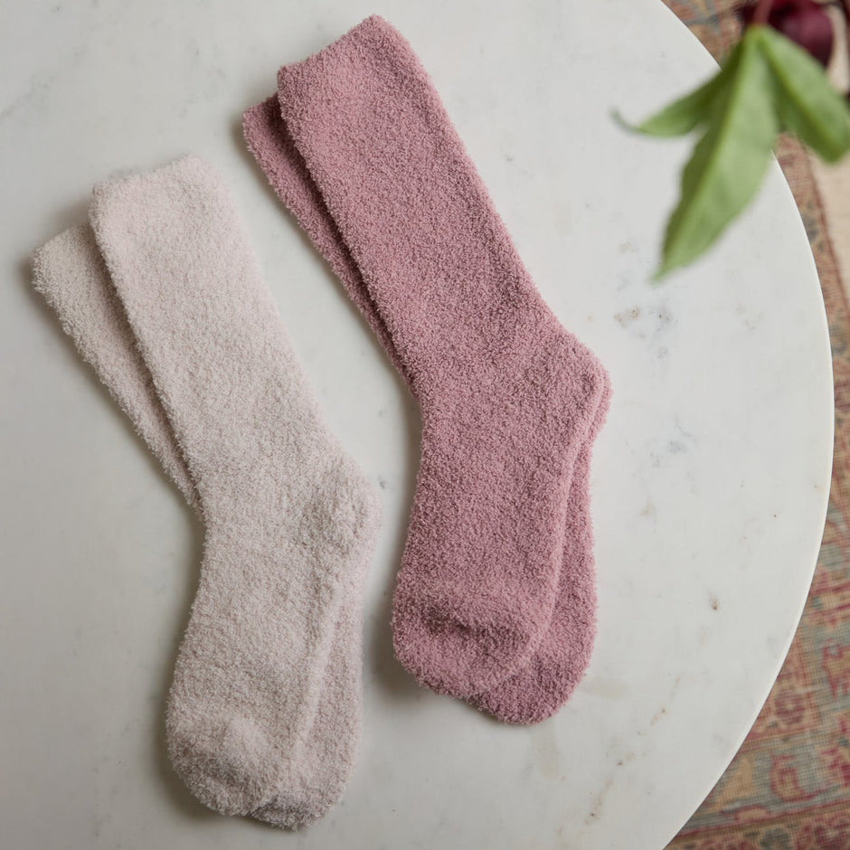 Teaberry/Heathered Stone, Two pairs of plush, textured crew socks, one in dusty rose pink and the other in a very light warm beige, arranged on a white marble surface.