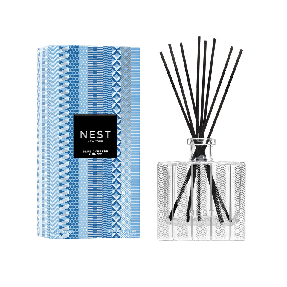 Nest New York Blue Cypress & Snow reed diffuser, featuring a clear glass bottle with black reeds and a blue patterned box.
