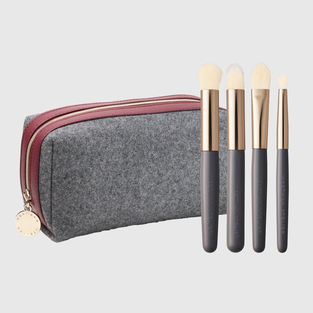 Westman Atelier The Refining Brush Edit four gold and gray brushes beside the exclusive gray felt travel case with burgundy trim