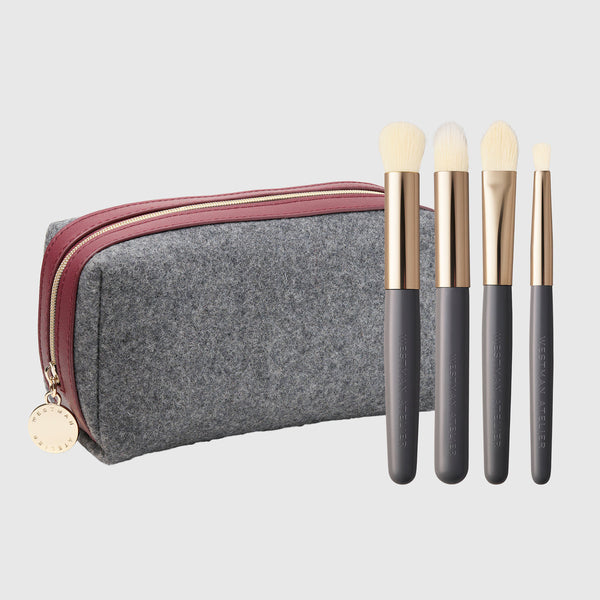 Westman Atelier The Refining Brush Edit four gold and gray brushes beside the exclusive gray felt travel case with burgundy trim