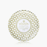 Decorative Voluspa candle packaging with gold intricate design on a white background