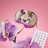 Cosmetic bag with product, tube of cream, and orchid flower on pink background