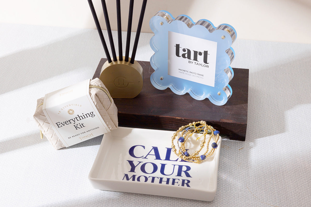 Assortment of gifts for a dorm room, including a picture frame, scented diffuser sticks, and a tray that says "Call your mother".