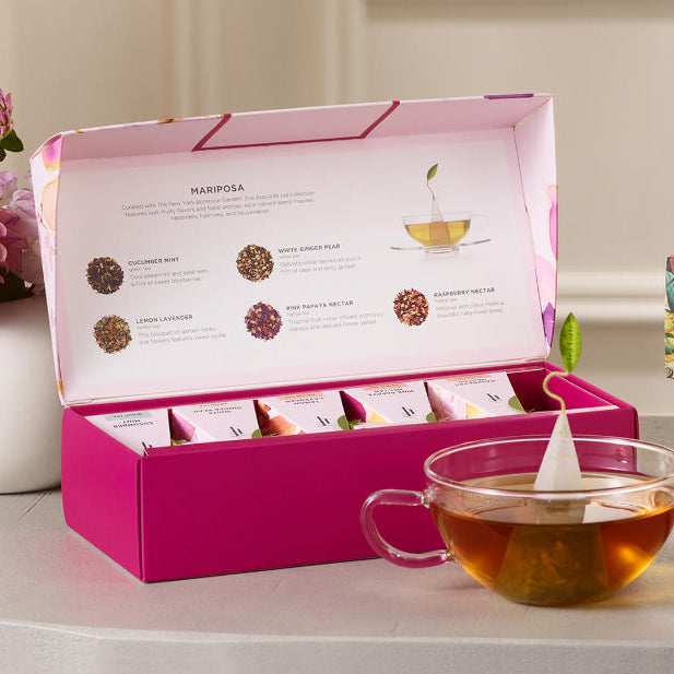 Mariposa Petite Presentation Box of 10 pyramid tea infusers, open on a table with a glass cup of tea