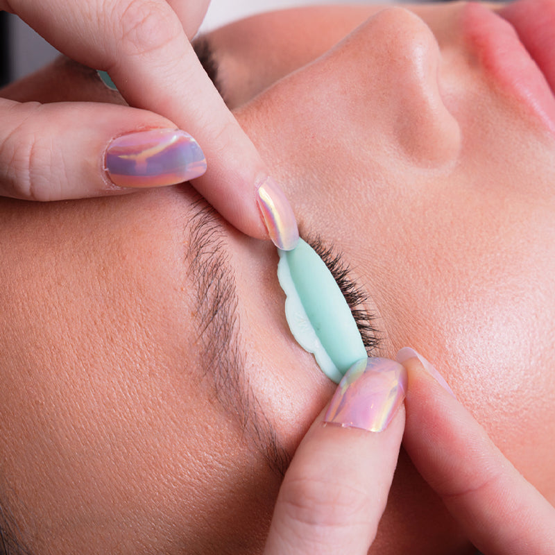 Person applying eyelash extensions with a tool