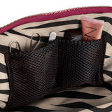 KUSSHI | Vacationer Makeup Bag — Wine/Zebra, Close-up of the inside of a cosmetic bag with a zebra-print fabric lining, a magenta zipper, and black mesh organizer pockets holding small makeup items.