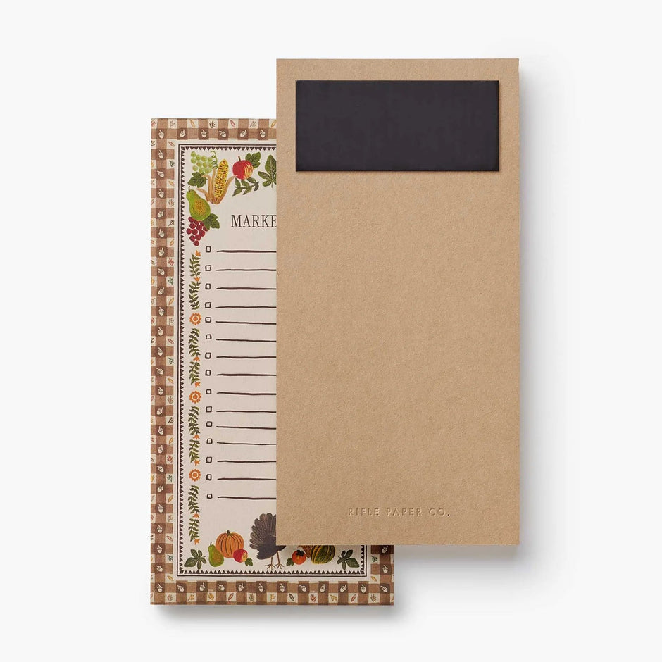 A kraft paper notepad with a black chalkboard-style top section and autumn-themed border, shown next to a matching patterned notepad page on a clean white background.