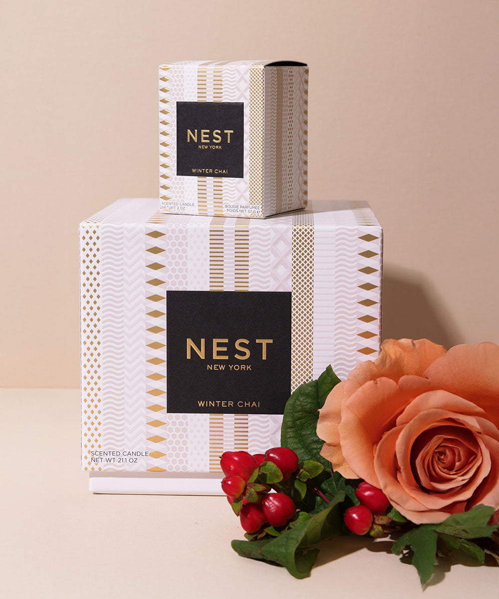 A Nest New York Winter Chai scented candle box set, featuring a large white box with gold geometric patterns and a smaller matching candle box stacked on top. The boxes have black labels with gold lettering.