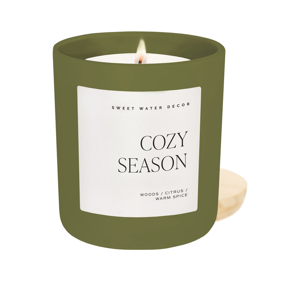 Sweet Water Decor Cozy Season 15oz soy candle in matte olive green jar with lit flame