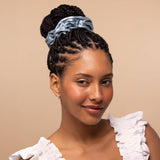 Woman wearing haze blue satin sleep scrunchie in updo hairstyle against neutral background